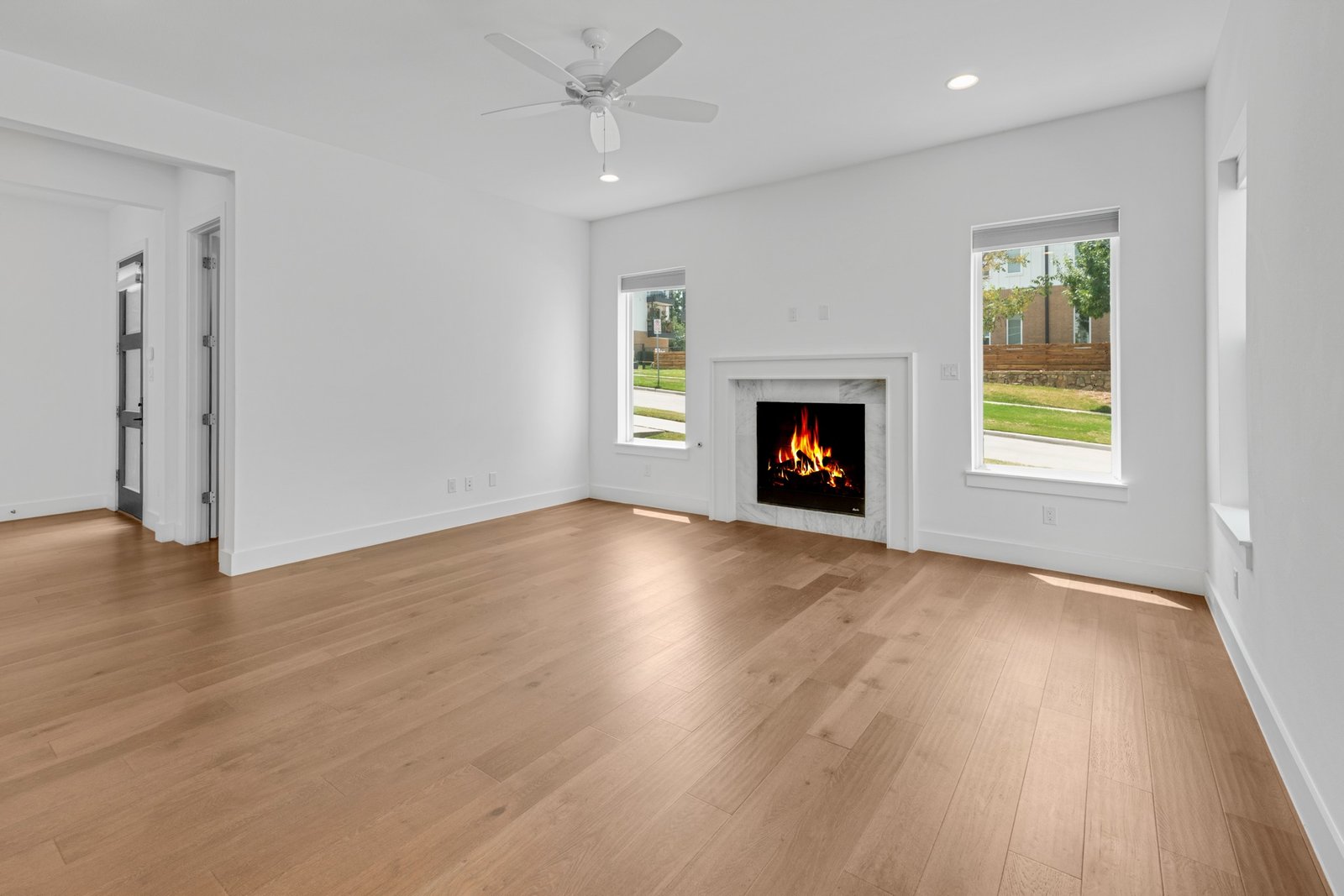 Living room at 2249 Bird St with a fire lit, oak floors, and two tall windows